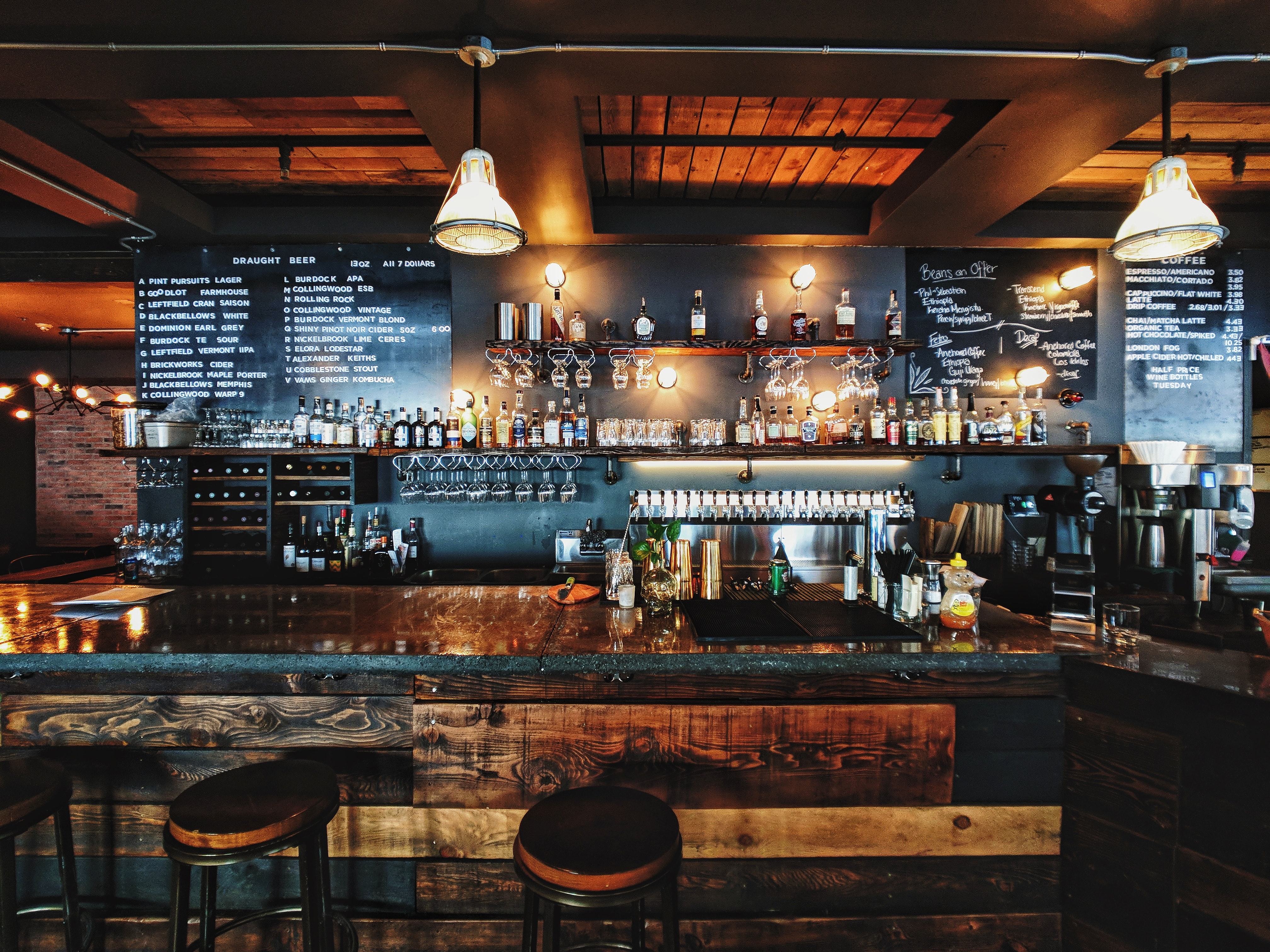 An empty bar on St. Patrick’s Day with dark wooden walls, several stools, and liquor on display